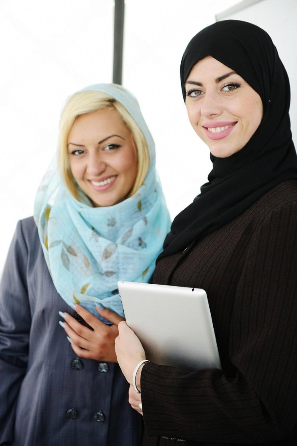 Two young women in hijabs holding a tablet during a BTEC class in the UAE
